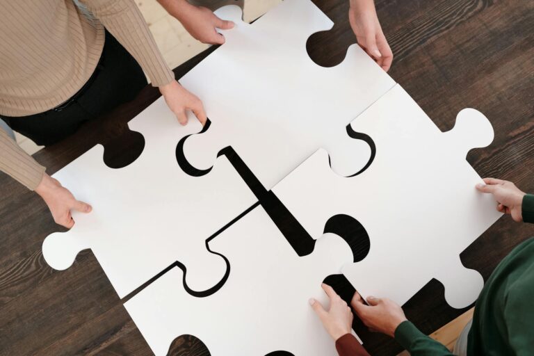 Zespół układający elementy puzzli – metafora połączenia procesów HR w jeden system oparty na wewnętrznej motywacja pracowników