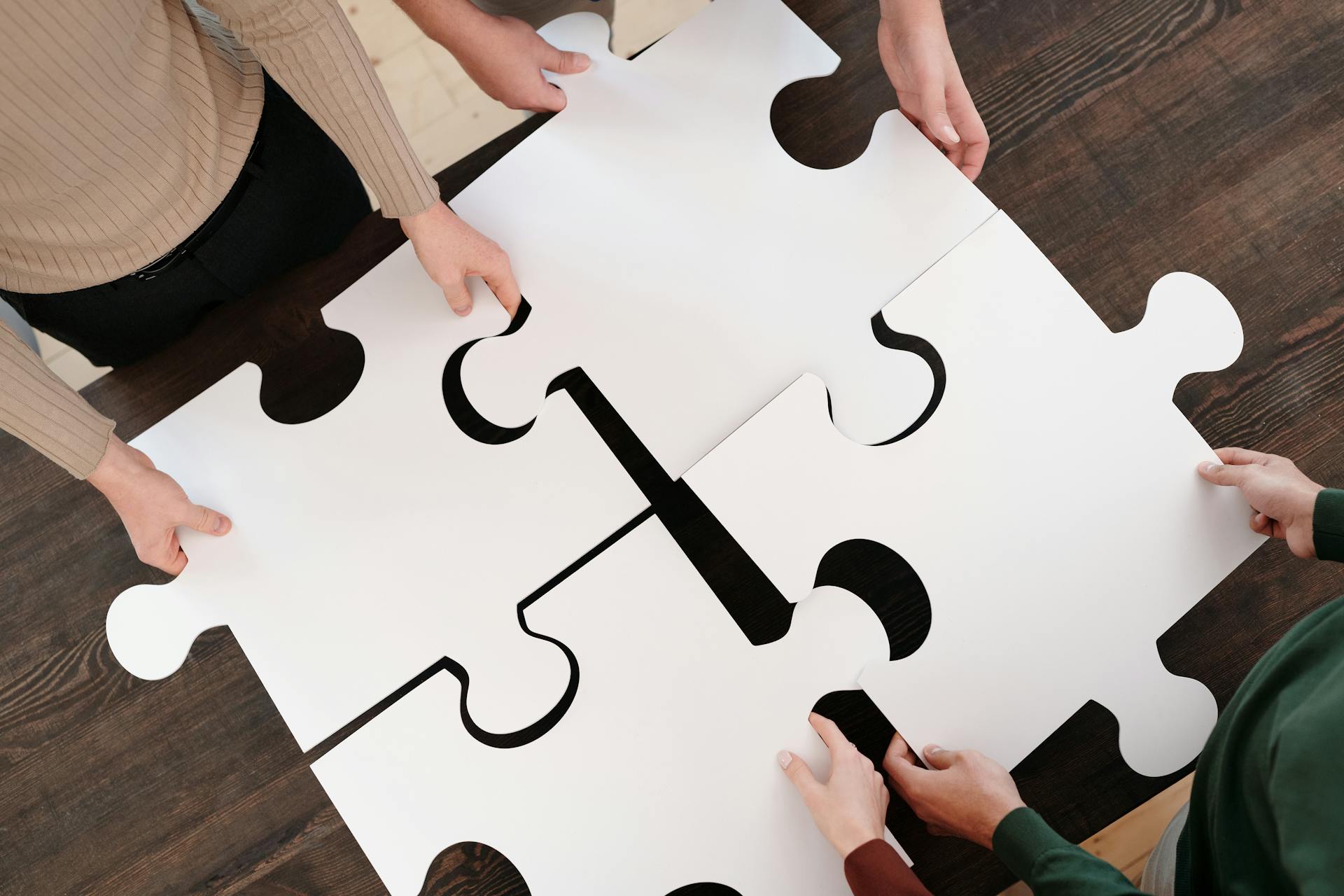 Zespół układający elementy puzzli – metafora połączenia procesów HR w jeden system oparty na wewnętrznej motywacja pracowników